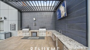 An outdoor kitchen area with two grills, a sink, and a brick backsplash.