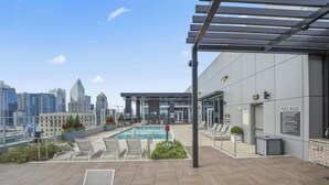 Un espace piscine sur le toit, avec des chaises longues, une piscine et une vue sur la ville.