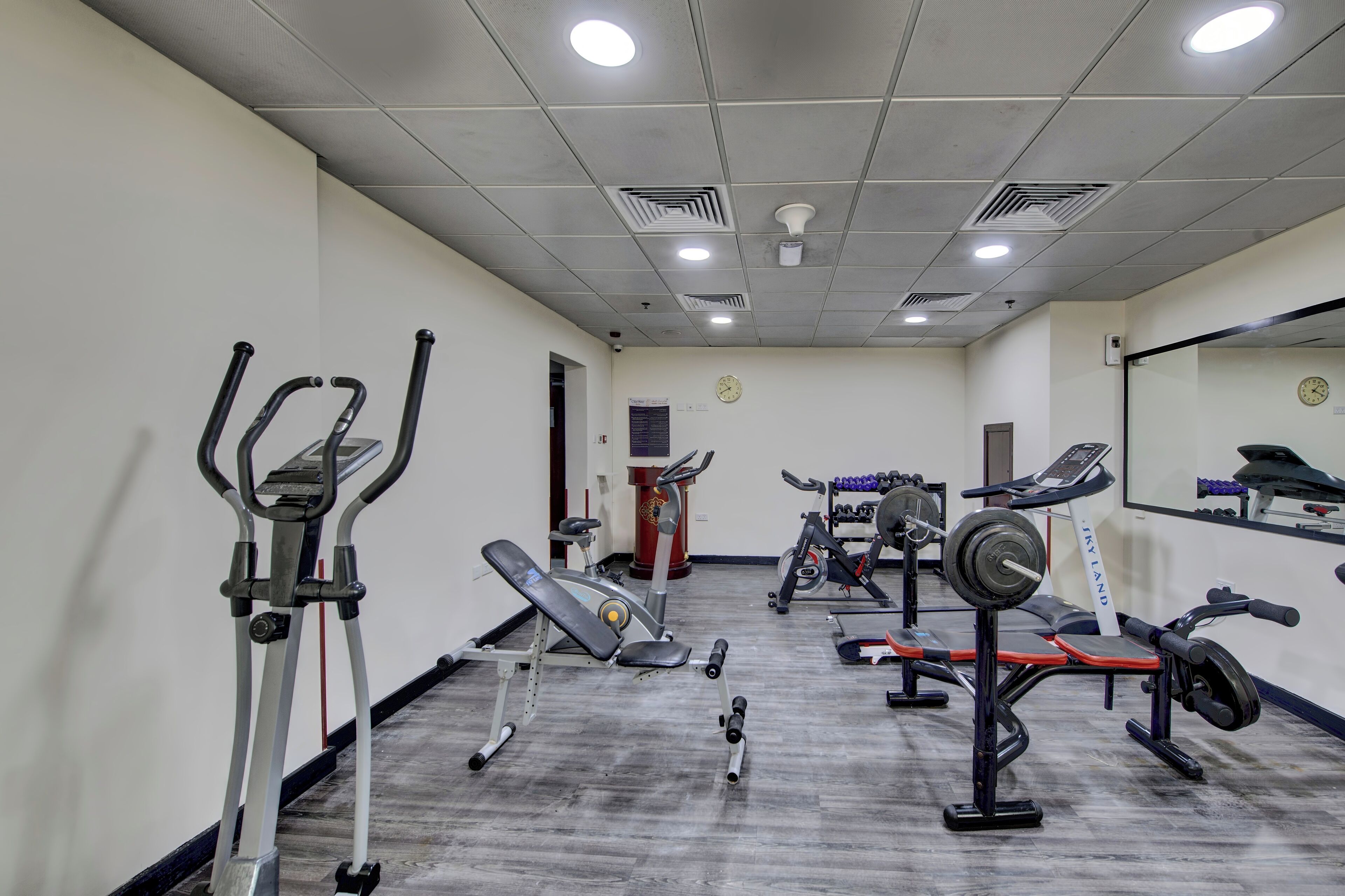 A gym with various exercise equipment, including treadmills, weight benches, and dumbbells.