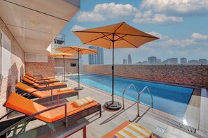 A rooftop pool area with lounge chairs and umbrellas, a clear view of the city skyline in the background. - City Stay Hotel Expo Centre (Sharjah)