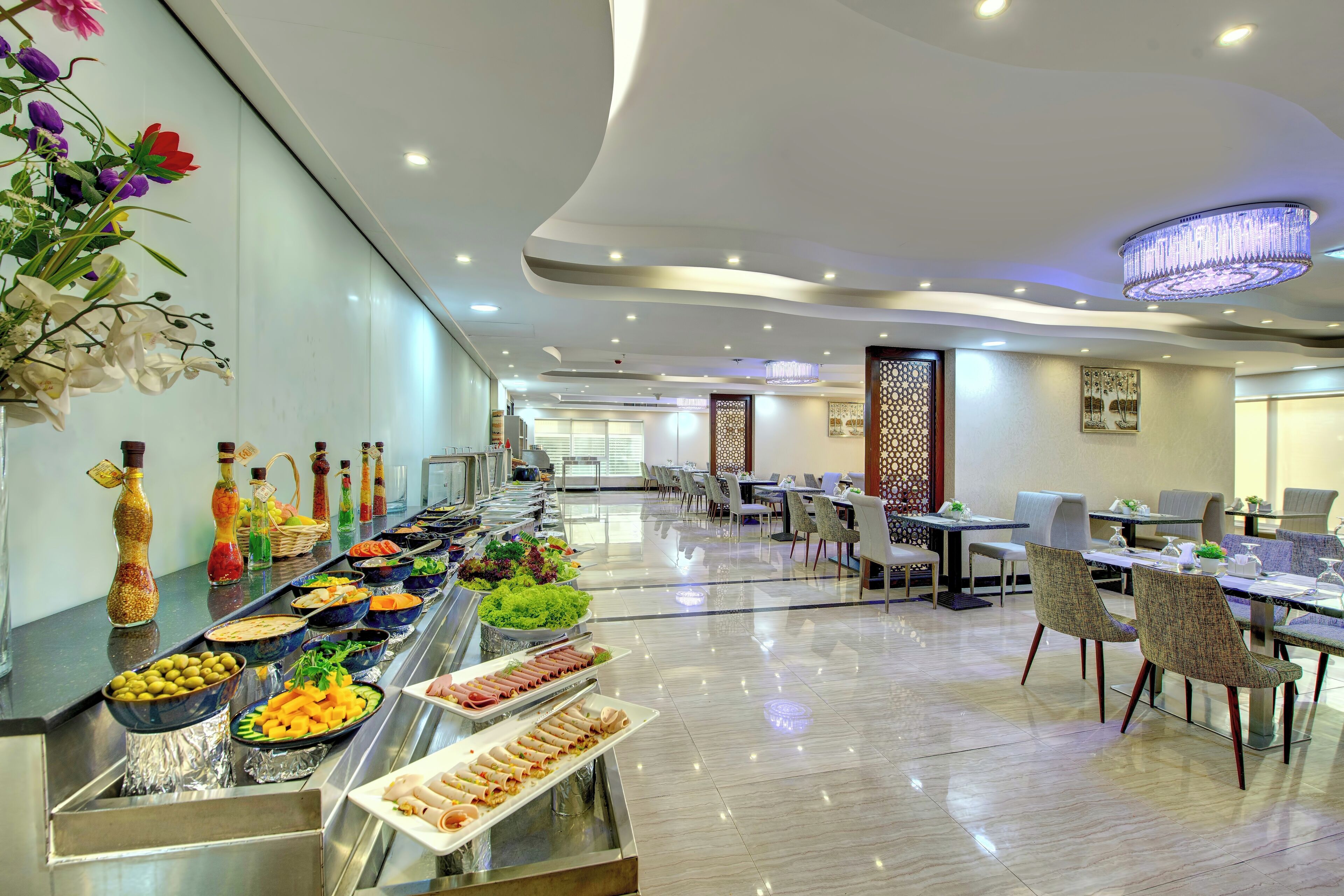 A buffet setup with various food items and a decorative wall with flowers.