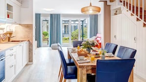 A modern kitchen with white cabinets, a wooden countertop, and a dining area with a wooden table and blue chairs.