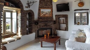 Un salón acogedor con chimenea de piedra, un televisor montado en la pared y un sofá blanco.