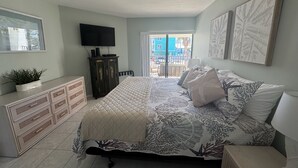 Un dormitorio con cama, cómoda, televisor y obras de arte.