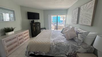 Un dormitorio con cama, cómoda, televisor y obras de arte.