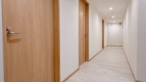A corridor with wooden doors and white walls. - Snowball Hostel (Furano)