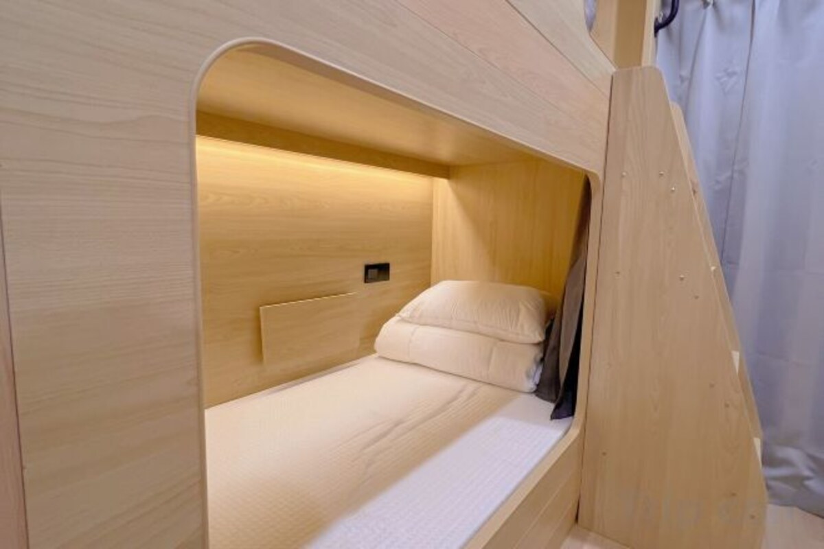 A single-occupancy wooden bunk bed with a headboard and a mattress.