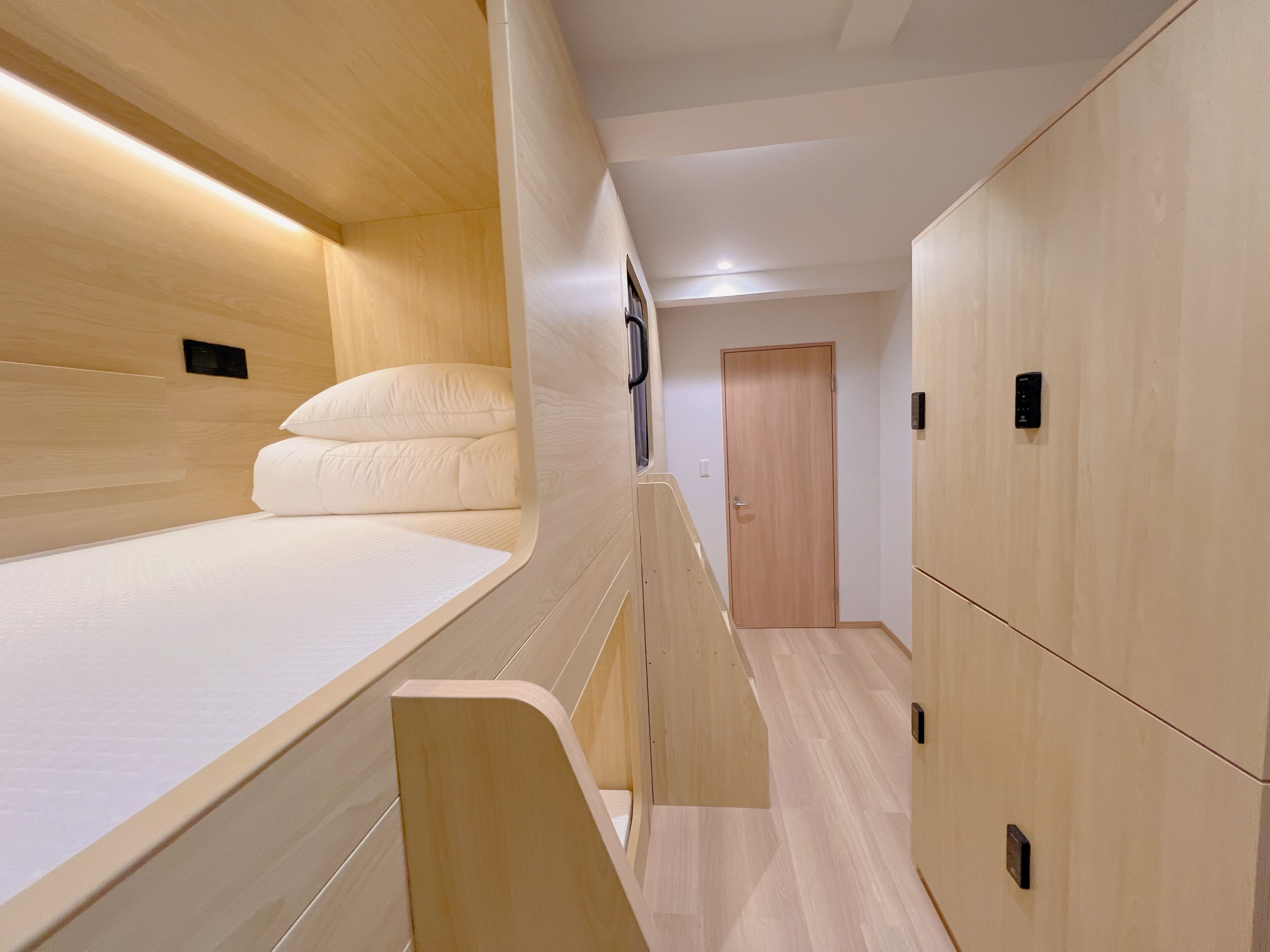 A modern, compact room with a bunk bed, wooden walls, and built-in storage cabinets.