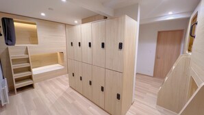A modern, well-lit room with a wooden wardrobe, built-in shelves, and a staircase. - Snowball Hostel (Furano)