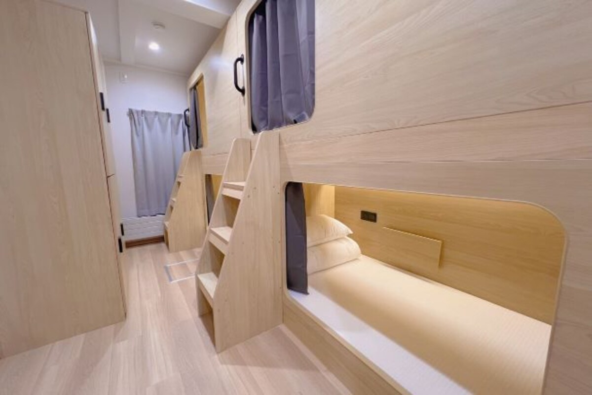 Un interior moderno y funcional, con paredes de madera y una pequeña zona de descanso con cama y ventana.