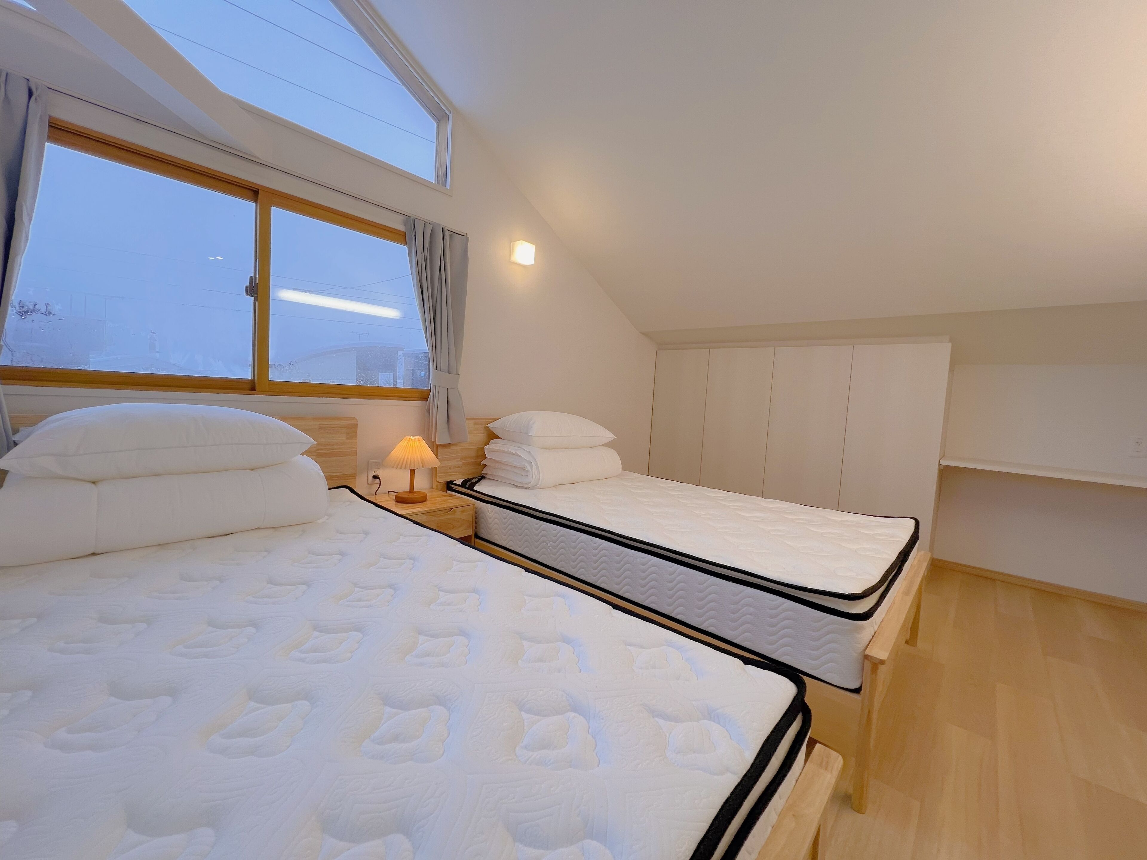 Ein modernes Schlafzimmer mit zwei Betten, einem Oberlicht und einem Nachttisch mit Lampe.