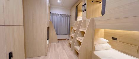 A modern, minimalist bedroom with a wooden floor, built-in wardrobe, and bunk beds.