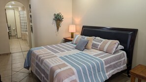 Relax in a spacious room with a large bed, nightstand, and bathroom featuring a toilet and towel rack.