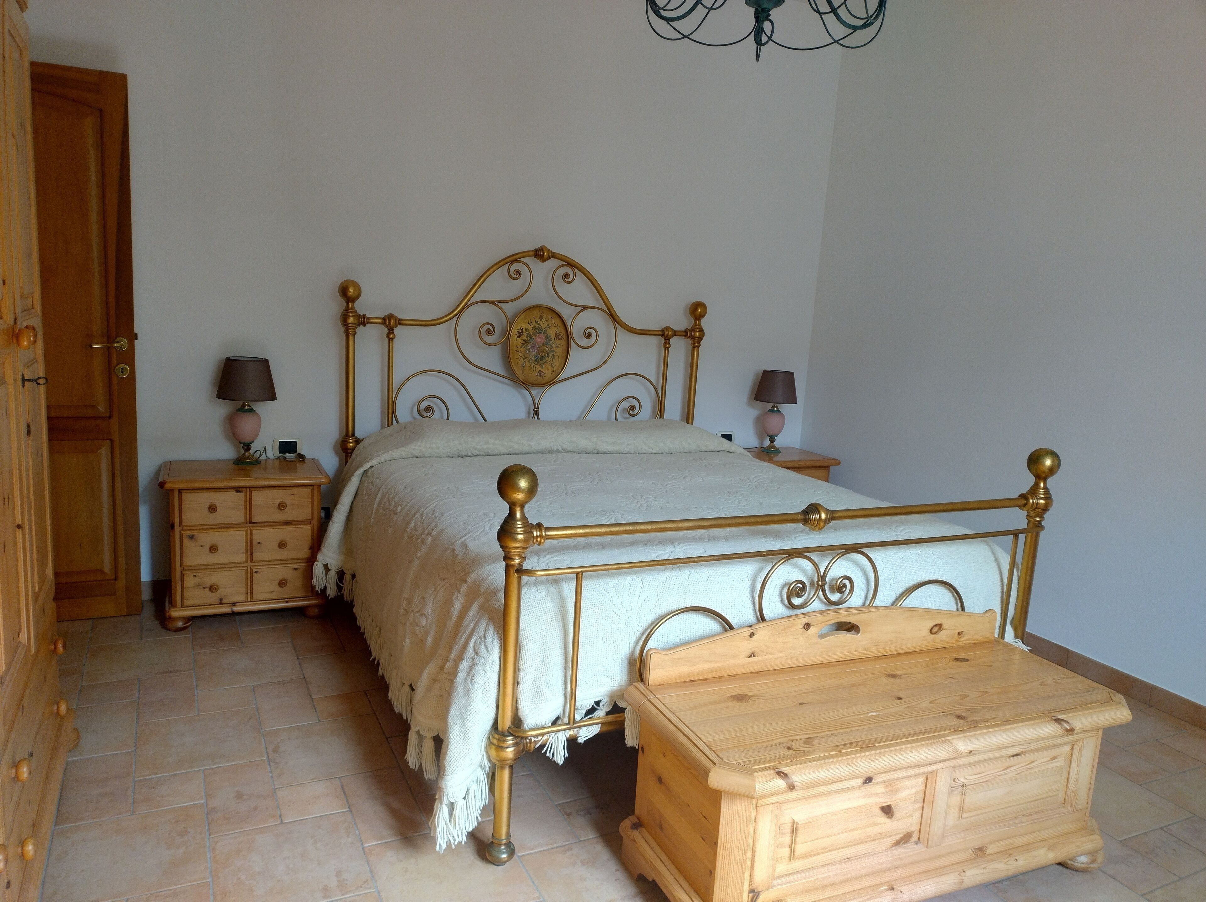 A bedroom with a bed, two bedside tables, a wooden chest, and a door.