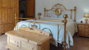 Une chambre à coucher avec une armoire en bois, un lit avec un cadre en métal, une table de chevet et une commode.
