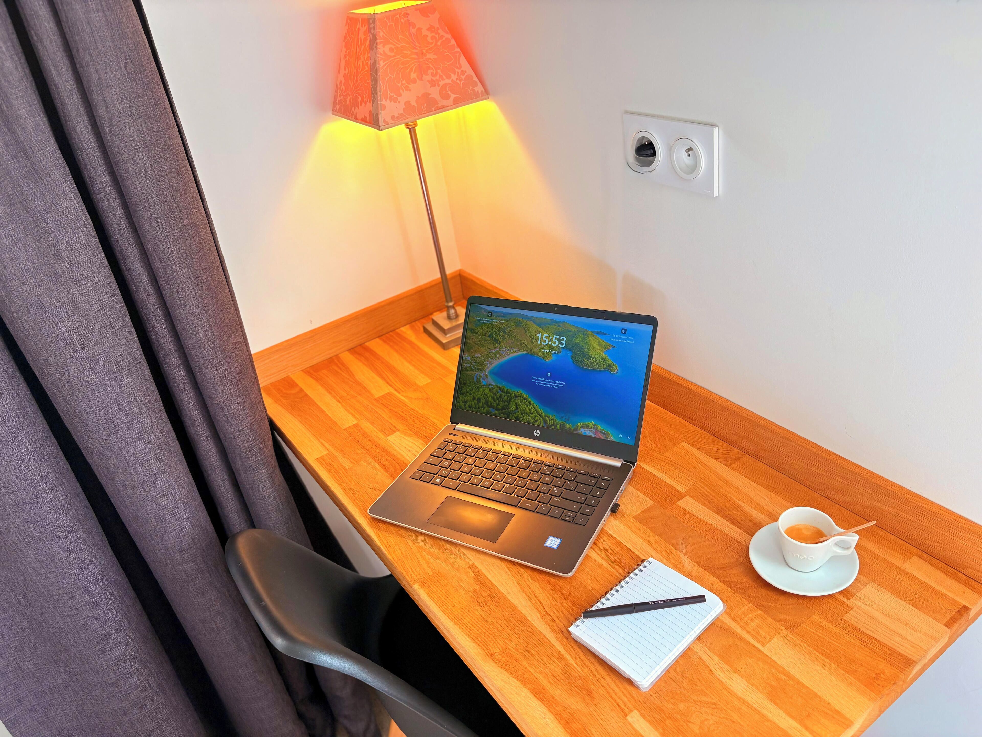 Un bureau en bois avec un ordinateur portable, une tasse de café et un carnet.