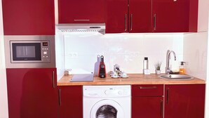 A compact kitchen with a microwave, a washing machine, and a sink. - Seclin Appartements (Seclin)