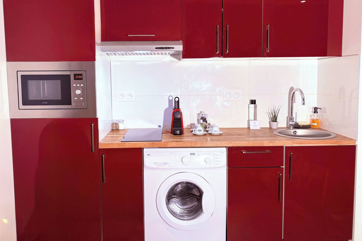 A compact kitchen with a microwave, a washing machine, and a sink.