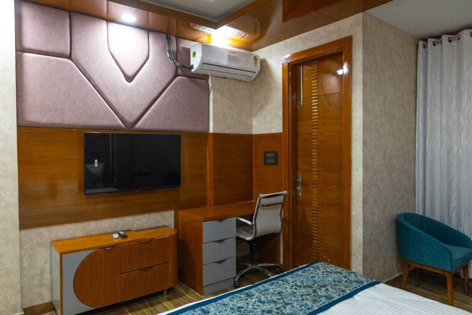A bedroom with a bed, a desk, a chair, a TV, and a wardrobe.