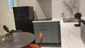 Une cuisine compacte dotée d’un four encastré, d’un évier et d’un coin repas avec une table et des chaises.