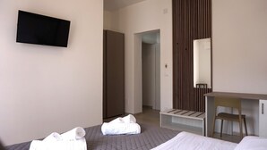 A hotel room with a bed, a desk, a chair, a TV, and a bathroom door. - La Scala del Moro Rooms- Dolce Risveglio (Lampedusa)