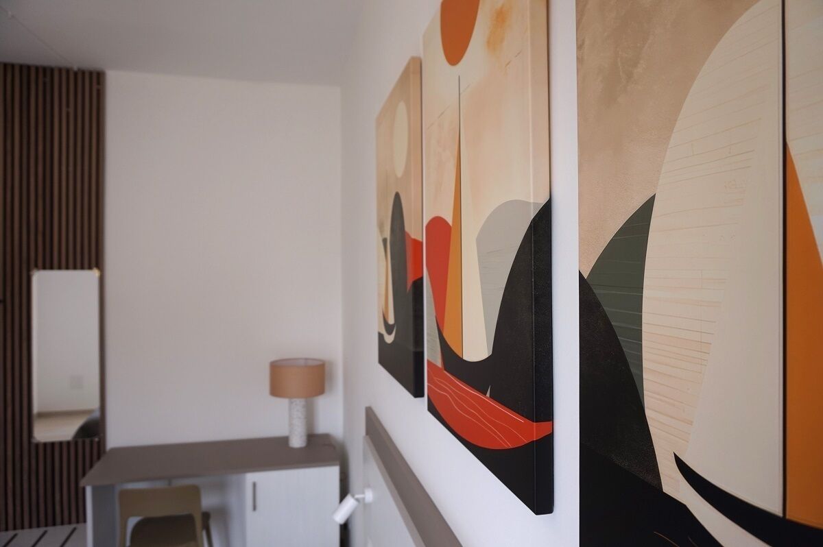 A modern room with abstract wall art, a desk, and a lamp.