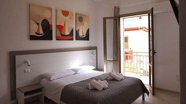 A modern hotel room with a bed, bedside tables, and artwork on the wall. - La Scala del Moro Rooms- Dolce Risveglio (Lampedusa)