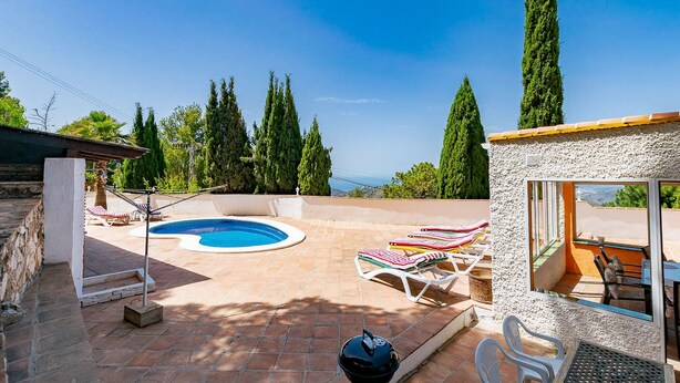 Un espace piscine avec des chaises longues et un barbecue.
