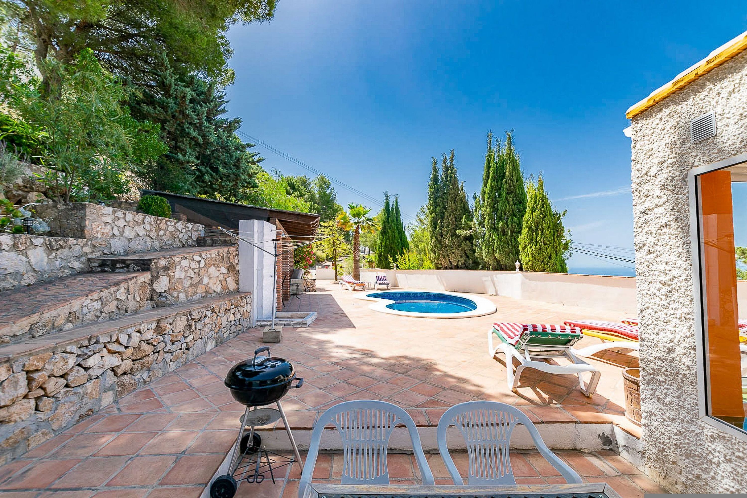 A patio with a barbecue, outdoor seating, and a swimming pool.