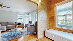 Un salón acogedor con un sofá, un sillón y una mesita con flores.
