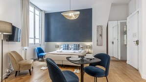 A modern hotel room with a large bed, a dining table with chairs, a TV, and a large window. - Parc Monceau - Studio - 2 personnes (Paris)