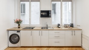 A modern kitchen with a washing machine, a microwave, a sink, and a toaster. - Parc Monceau - Studio - 2 personnes (Paris)