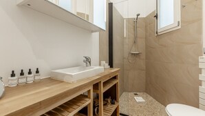 A modern bathroom with a wooden vanity, a white sink, and a shower area. - Parc Monceau - Studio - 2 personnes (Paris)