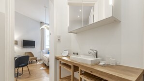 A modern bathroom with a wooden vanity, a mirror, and a sink. - Parc Monceau - Studio - 2 personnes (Paris)