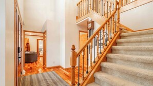 A staircase with wooden balusters and carpeted steps leading to a second floor.