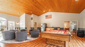 A spacious living area with a pool table, comfortable seating, and a kitchen area.