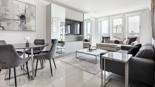 A modern living room with a dining area, a kitchen, and a large window with a city view.