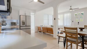 A modern kitchen with white cabinets, a built-in oven, and a dining area with wooden chairs and a table. - Casa Bella with private swimming pool (Aguada)