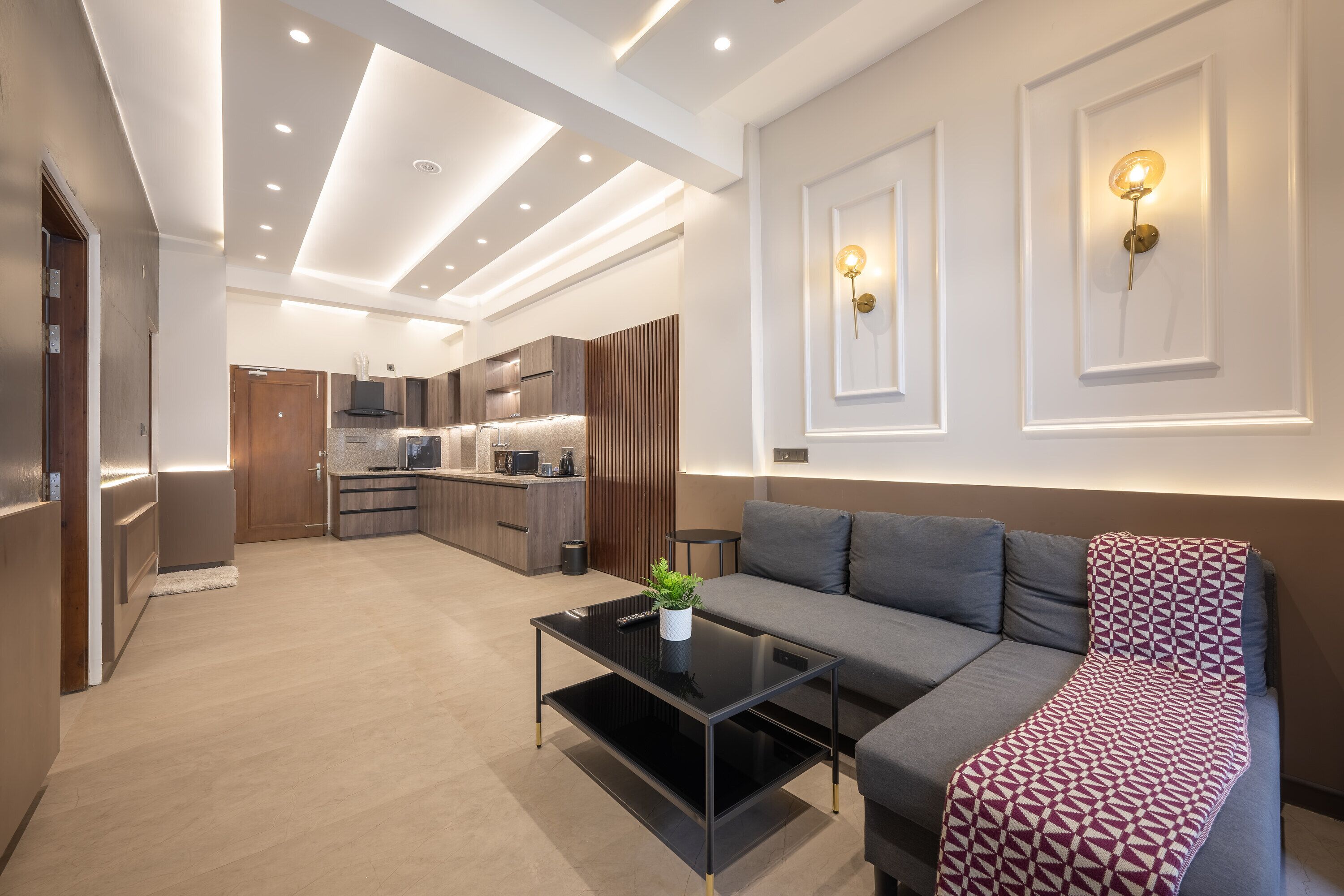 Een moderne woonkamer met een bank, een salontafel en een keuken op de achtergrond.