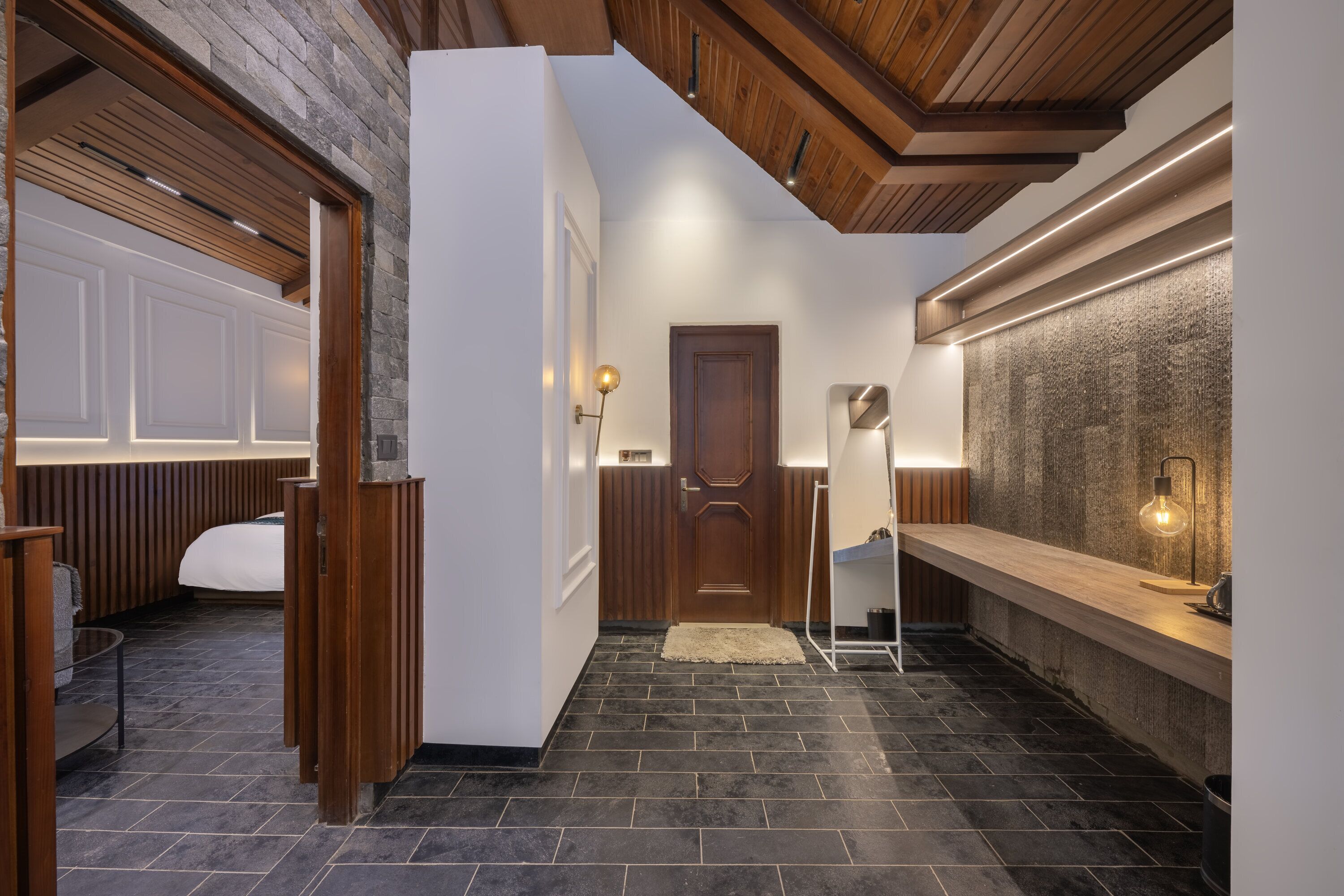 A modern interior with a wooden ceiling, a stone wall, and a long counter with a light fixture.