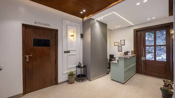 Un área de cocina moderna con una puerta de madera que dice 'KITCHEN', una pequeña mesa con una planta y una lámpara sobre la puerta.