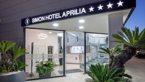 The exterior of Simon Hotel Aprilia with a modern design, featuring a reception area, a staircase, and potted plants. - SIMON HOTEL APRILIA (Aprilia)