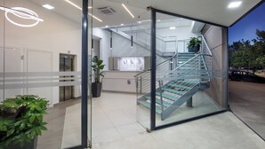 A modern building with a glass entrance, a staircase, and a reception desk. - SIMON HOTEL APRILIA (Aprilia)