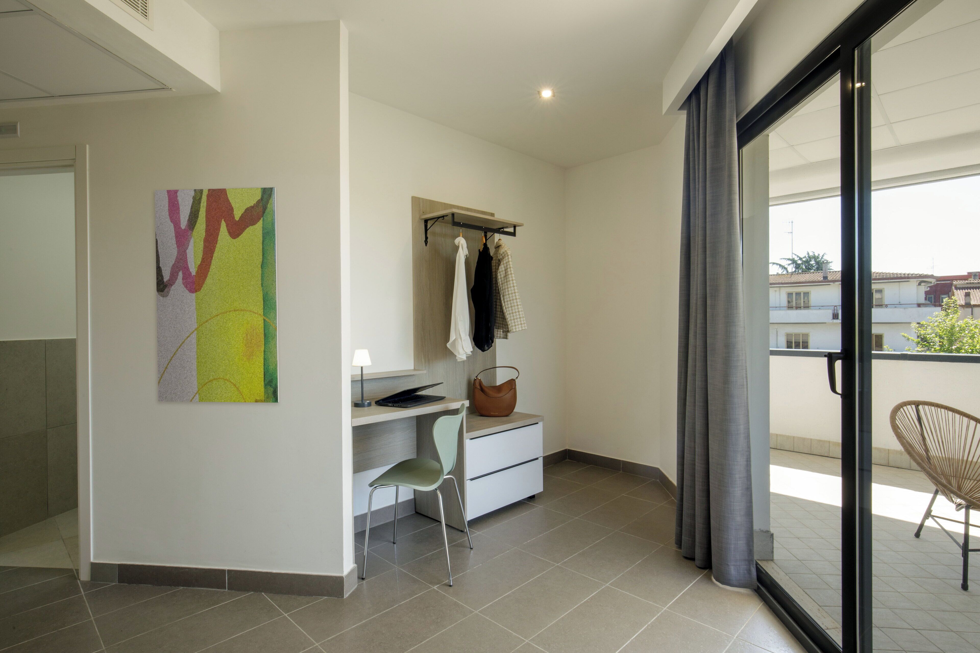 Una habitación moderna con escritorio, silla y un ventanal amplio.