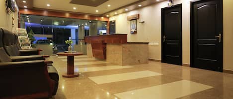 A hotel lobby with a reception desk, a reception area, and two black doors labeled "Office".