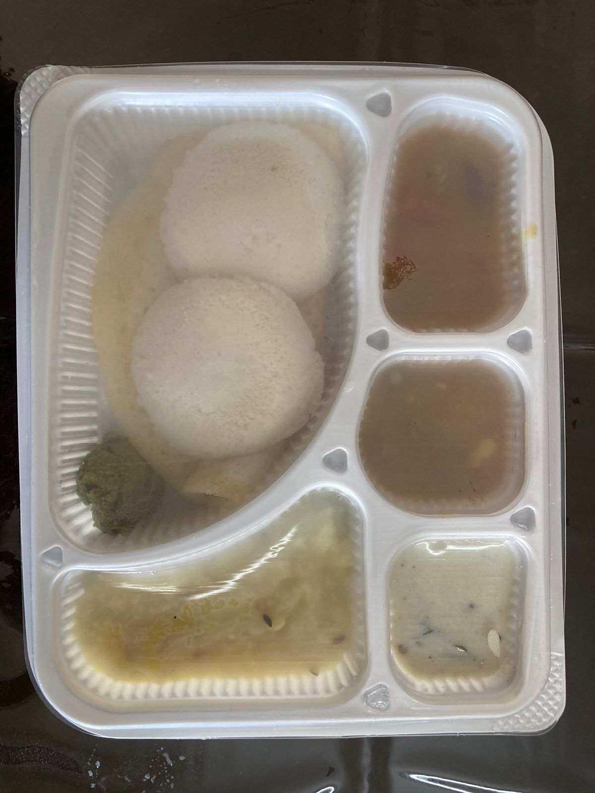 A plastic container with compartments containing food items.