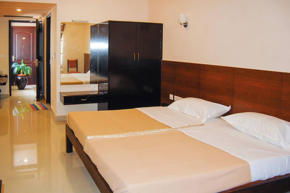 Ein Hotelzimmer mit Bett, Schrank, Spiegel und einer Topfpflanze.