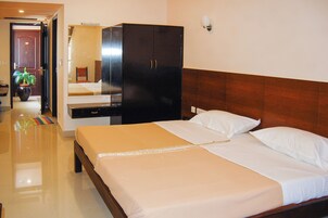 Una habitación de hotel con una cama, un armario, un espejo y una planta en maceta.