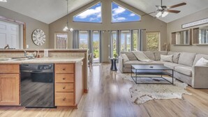 A spacious living area with a large sofa, a coffee table, and a kitchen with a dishwasher.