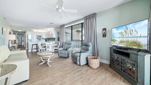 Un salon avec un canapé, deux fauteuils, un téléviseur et une cheminée.